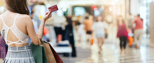 Rear view, young asian woman holding shopping bags and credit card to shopping in store