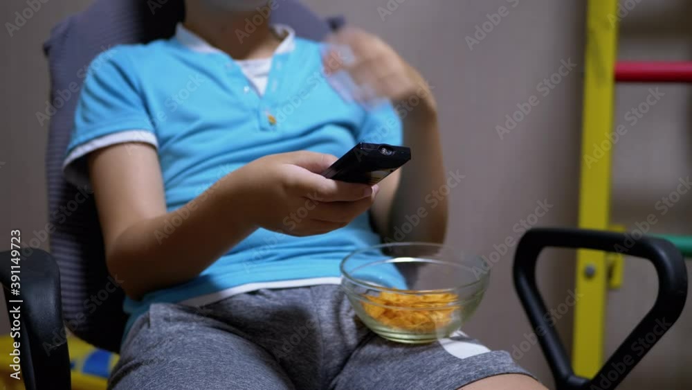 Child Sits in Front of TV, Eats Potato Chips, Changes Channels a Remote Control Child Sits in Front of TV, Eats Potato Chips, Changes Channels a Remote Control