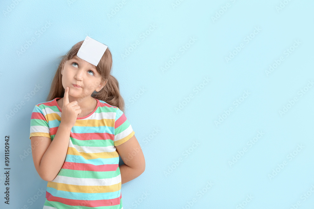 Thoughtful little girl with blank note paper on her forehead against color background Thoughtful little girl with blank note paper on her forehead against color background