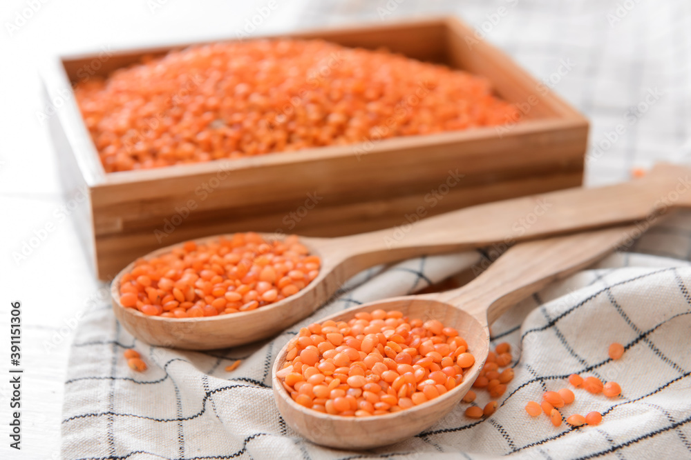 Spoons and box with raw lentils on table Spoons and box with raw lentils on table