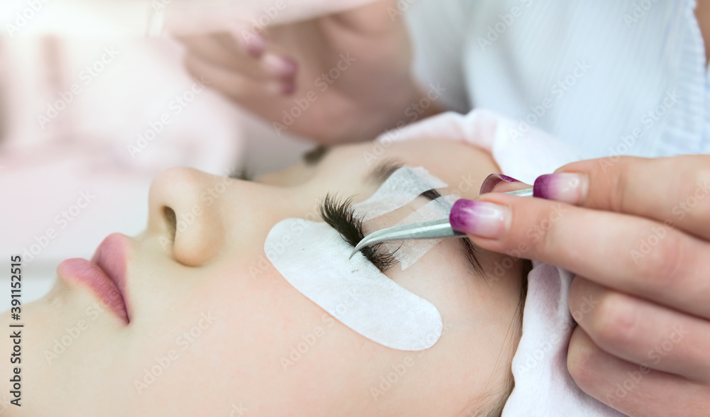 Naklejka premium Eyelash Extension Procedure. Woman Eye with Long Eyelashes. Beautiful young girl eyelash extensions.