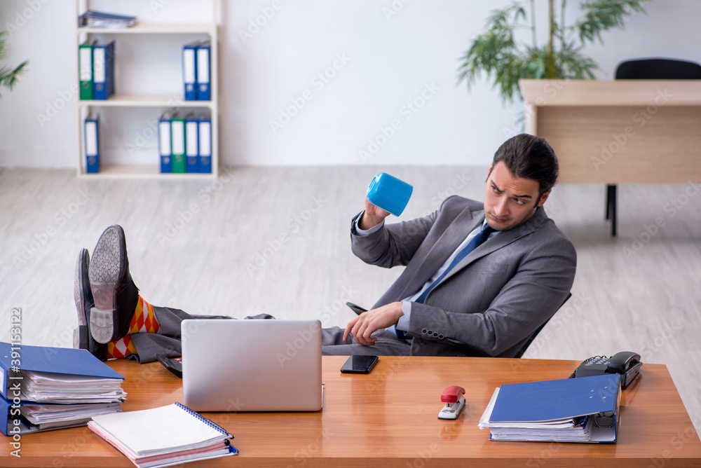 Young male employee drinking coffee in the office Young male employee drinking coffee in the office