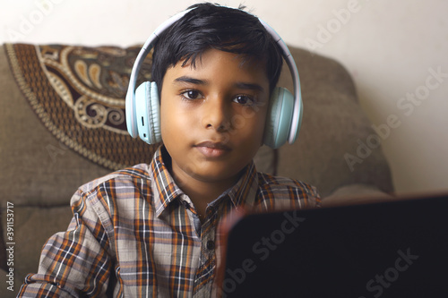 Portrait of Indian little boy using laptop while attending the online class at home	
 photo