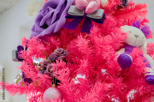 Pink Christmas tree with purple decorations. Unusual interior decor for the new year. Christmas mood.