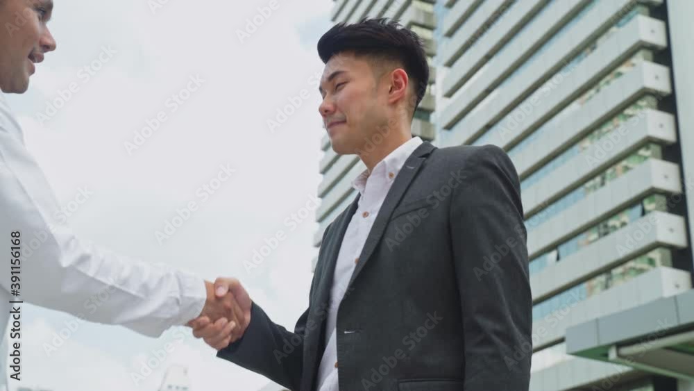 Asian young male manager make a handshake with employee and admire him Asian young male manager make a handshake with employee and admire him