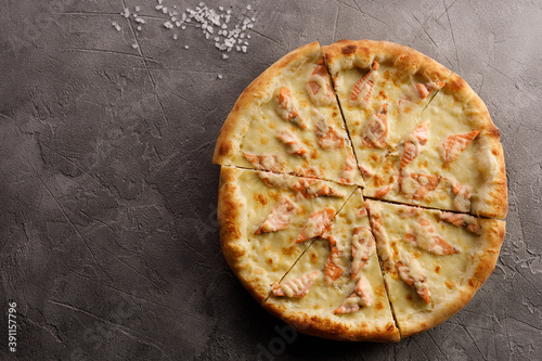Appetizing pizza with salmon on a textured background. Delicious food concept. Close-up.