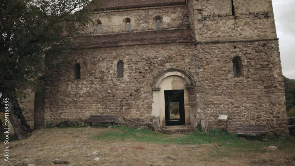 Tilting down-up shot of an old medieval Saxon fortified stone-built church. This church is placed in Transylvania in the town of Cisnadioara, Sibiu County, Romania.