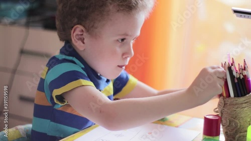 Little boy draws at a table at home. The child is engaged in creativity, studying at home, video