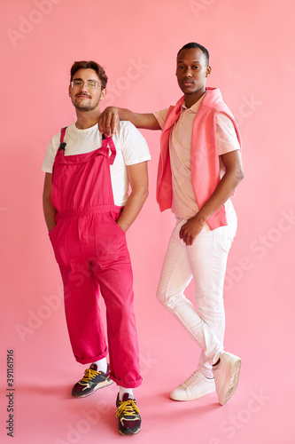men of different races have close friendship, black man leaned on european man. isolated on pink background. african and caucasian people