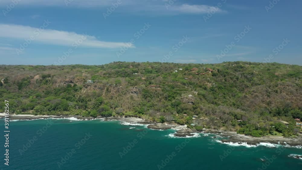 Beautiful drone view of a tropical coastline with waves hitting the beach full of trees. Clear blue skies Beautiful drone view of a tropical coastline with waves hitting the beach full of trees. Clear blue skies