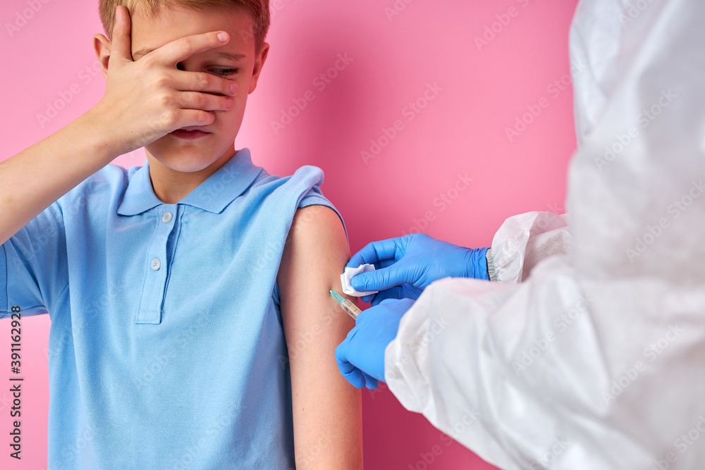 male doctor giving vaccine shot to frightened child boy, kid is afraid of injections. prevention, protection and immunization concept male doctor giving vaccine shot to frightened child boy, kid is afraid of injections. prevention, protection and immunization concept