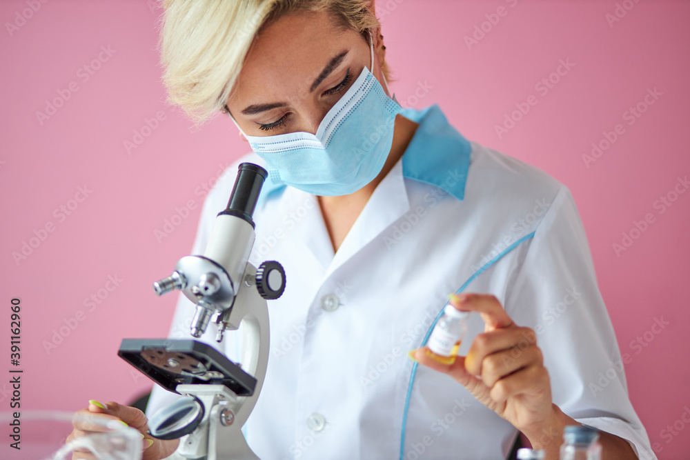 young scientist woman investigating a vaccine to cure coronavirus disease, use microscope. isolated on pink background young scientist woman investigating a vaccine to cure coronavirus disease, use microscope. isolated on pink background