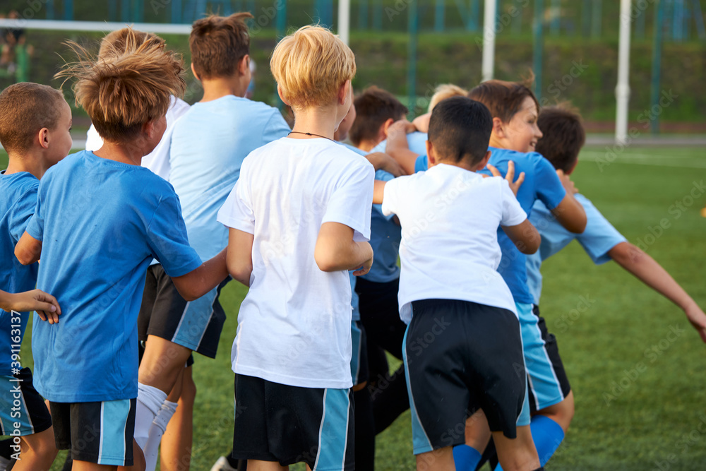 Obraz premium rear view on happy cheerful team of young football players celebrating their win in game, they run and have fun