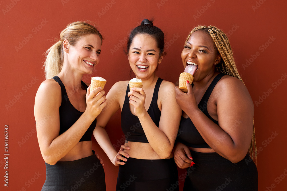 friendly charming diverse women eating sugar tasty yummy appetiser snack, delicious ice-cream, african caucasian and asian women isolated on red background