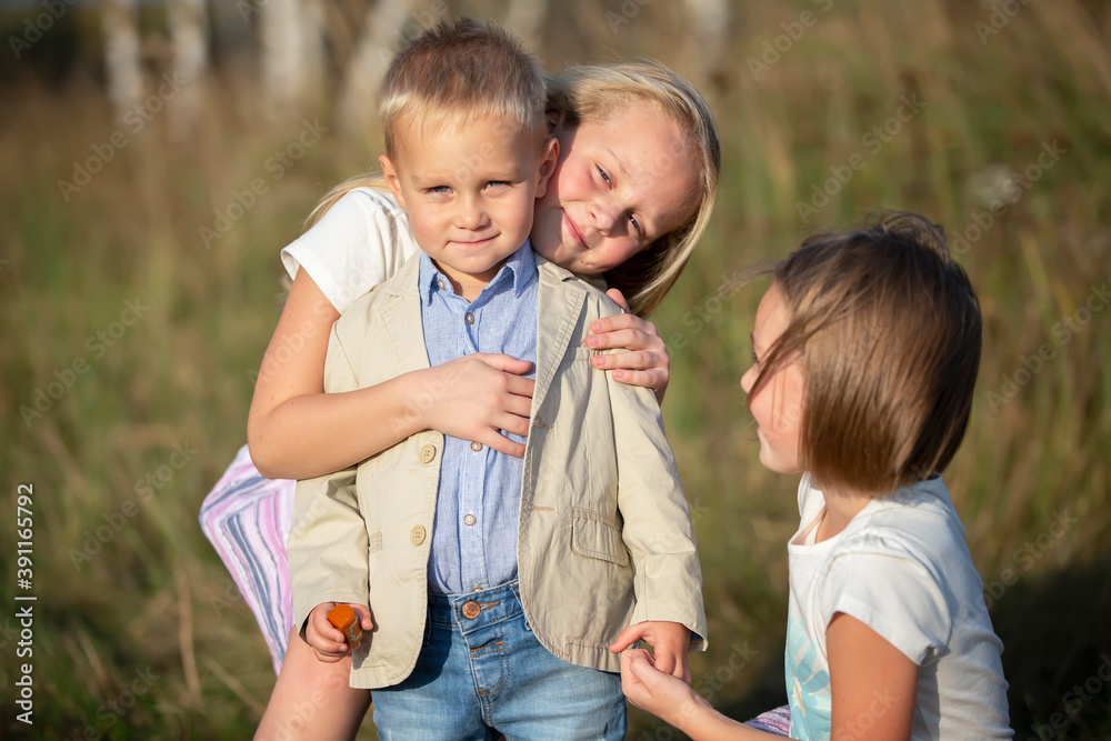 Fototapeta premium Happy family: sisters and little brother on a summer meadow.