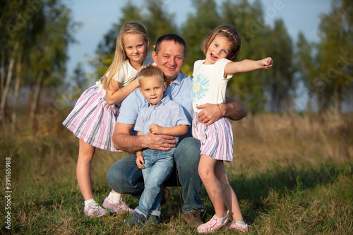 Dad with daughters and son looking into the camera. Happy father and children. © Светлана Лазаренко