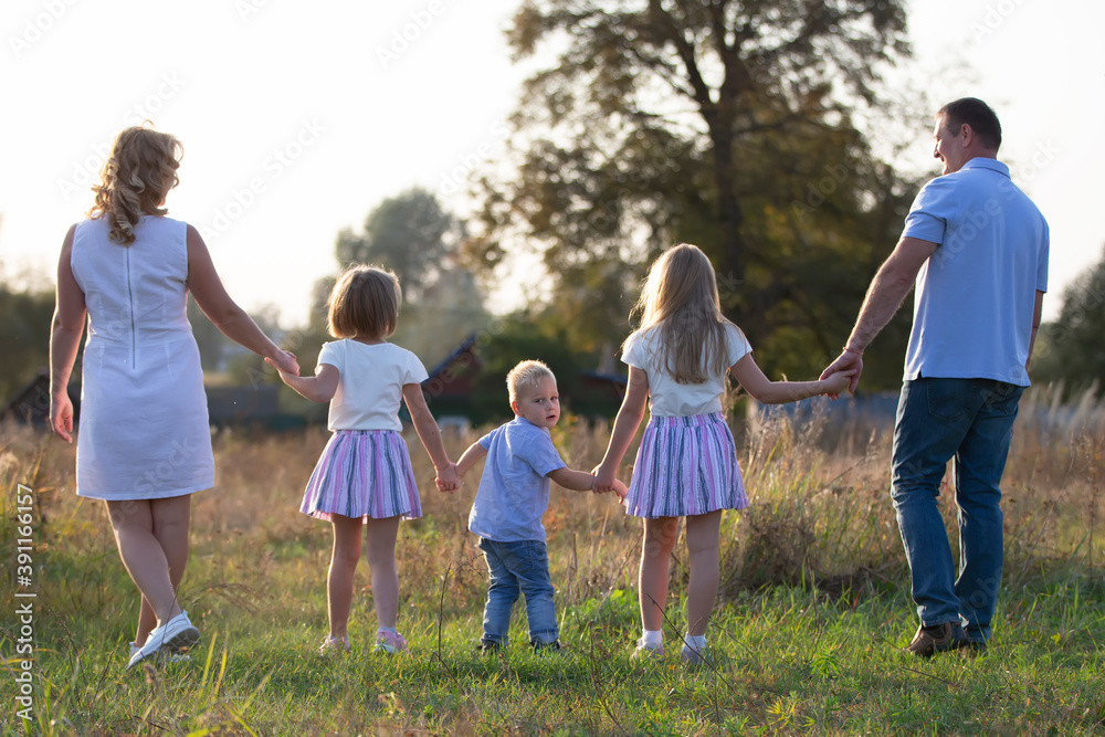 Fototapeta premium Happy family: mother, father, children, son and daughters in nature at sunset. Parents and children are walking together. The large family.