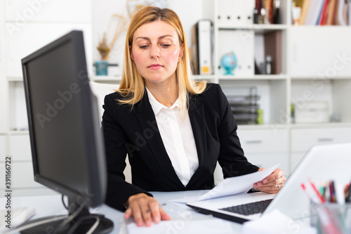 Portrait of confident businesswoman in formal wear working on laptop in business office