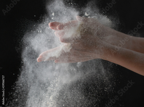 wave of hands with flour on a black background