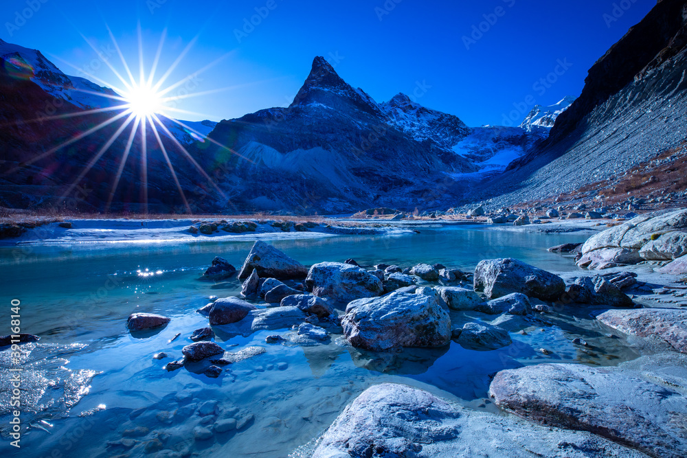 Sunrise with a river flowing through a valley in late autumn with snow capped mountains in the background