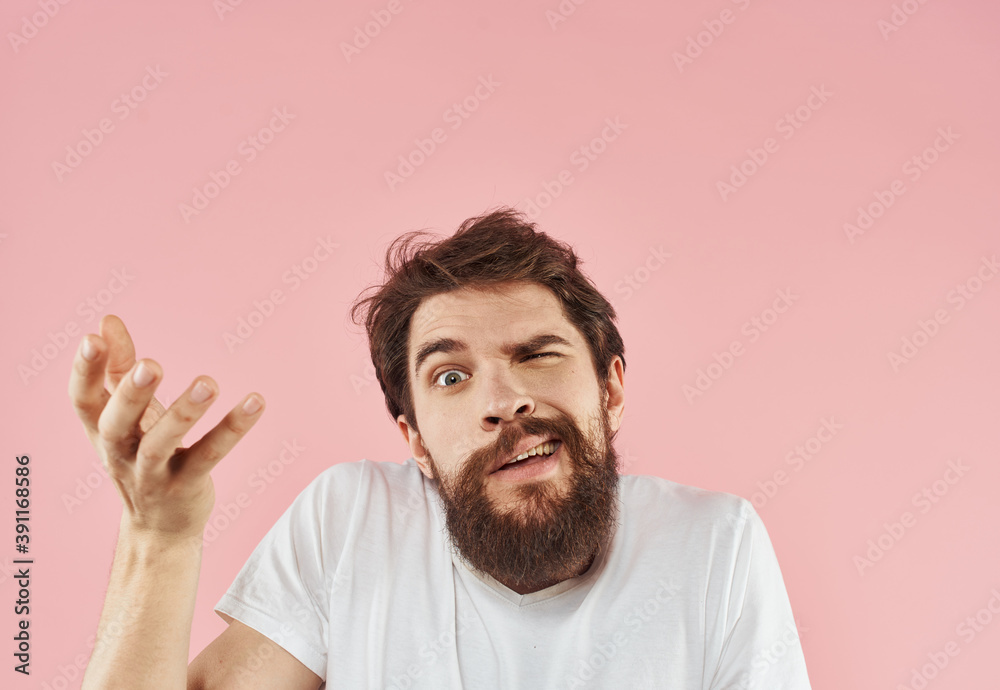 A man with a beard gestures with his hands on a pink background cropped view of a white t-shirt A man with a beard gestures with his hands on a pink background cropped view of a white t-shirt