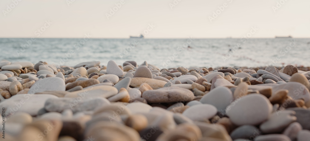 pebble beach at sunset. sea and ship in the background. Pebble close up. pebble beach at sunset. sea and ship in the background. Pebble close up.