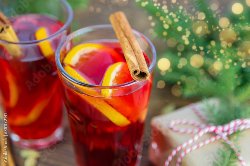 Close-up of two glasses of hot Christmas mulled wine and oranges, garnished with a cinnamon stick. Winter hot wine on wooden background