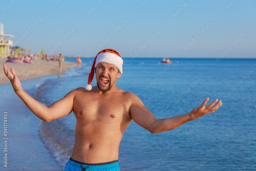 New year's eve on the beach by the sea. happy man in a Christmas hat sunbathing in the sun. blue sky as a copy of space
