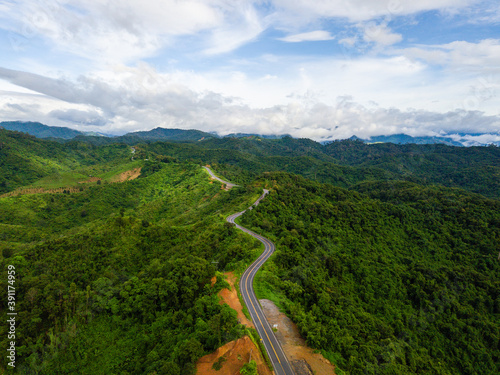 Aerial view of road In beautiful green forest and blue sky background