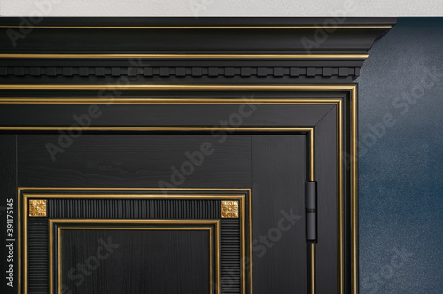 Classic black wooden entrance door with carved panels and Golden patina