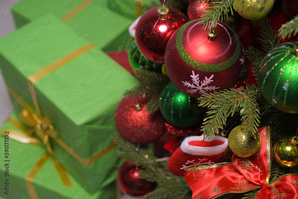 New year's gifts in green wrapping paper with gold ribbons under a Christmas tree decorated with red and green balloons: place for text, top view