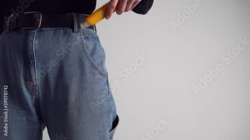 The man pulls a yellow utility knife from his jeans pocket