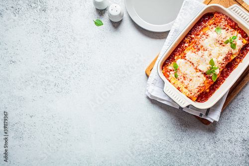 Traditional cannelloni with ricotta and spinach in tomato sauce in ceramic dish, top view. Italian food concept. photo