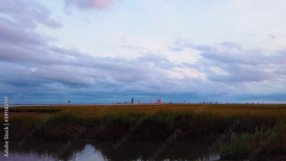 HD MOTIONLAPSE Straight pan from left to center and hold Atlantic City skyline in distance over waterway with mostly cloudy sky day to night with clouds turning pink, purple and blue HD MOTIONLAPSE Straight pan from left to center and hold Atlantic City skyline in distance over waterway with mostly cloudy sky day to night with clouds turning pink, purple and blue