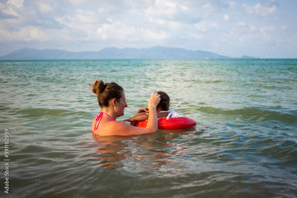 young mother and her baby Toddler swim in the sea. child in a special inflatable lifebuoy