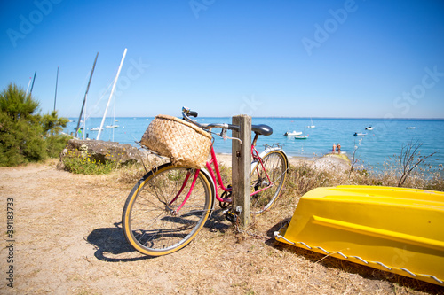 Vélo rouge en bord de mer laissé par un touriste parti à la plage.