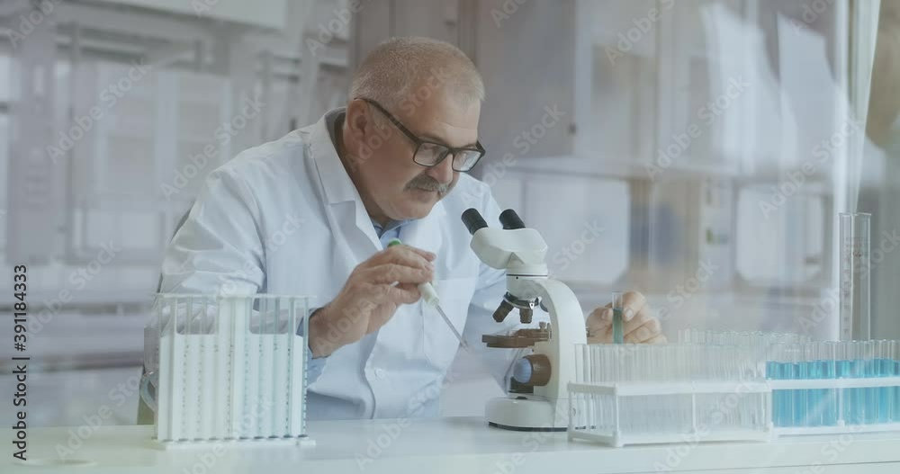 Male Research Scientist. He Sitting in a High-End Modern Laboratory with Beakers, Glassware, Microscope and Working Monitors Surround Him. Male Research Scientist. He Sitting in a High-End Modern Laboratory with Beakers, Glassware, Microscope and Working Monitors Surround Him.