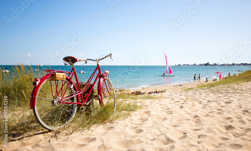 Leinwand Poster Vieux vélo rouge en bord de plage sur le littoral français.