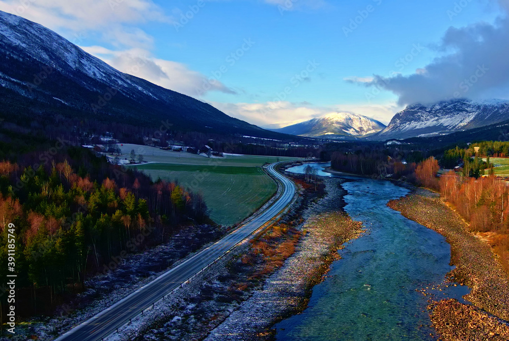 Mountain valley in autumn colors with a highway running along a turquoise glacial river.