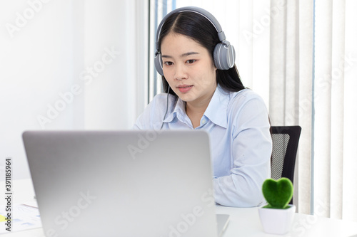 Young white Asian woman studying via the internet in her home office. © Puwasit Inyavileart