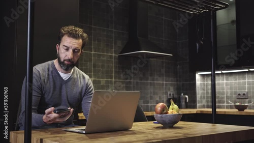 A man works with the computer from the kitchen of his house 