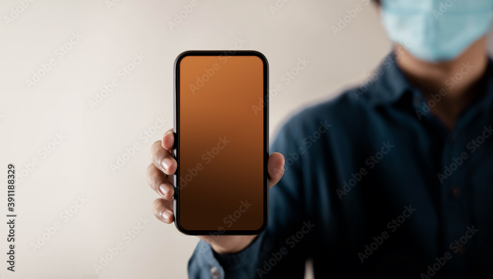 Mobile Phone Mockup Image. Display Screen is Blank. Person with a Surgical Mask on Face Holding a Smartphone towards the Camera. Front View