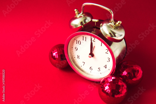 Beautiful vintage silver alarm clock and red Christmas balls on a bright red background. Time concept. Holiday routine