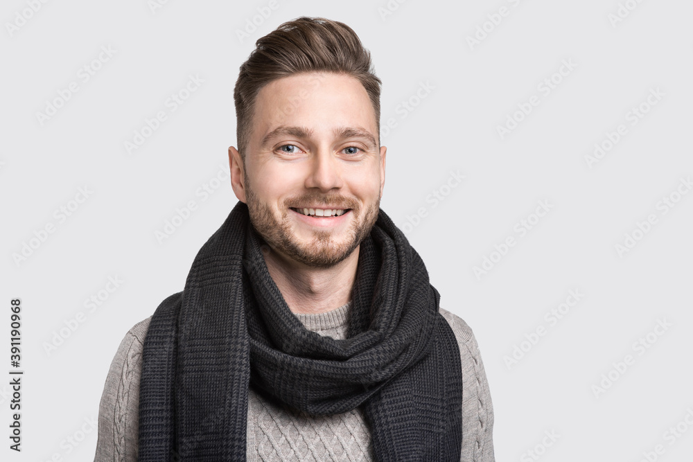 Portrait of handsome smiling young man wearing warm winter clothing. Laughing cheerful men studio shot. Isolated on gray background. People, male beauty, winter concept Portrait of handsome smiling young man wearing warm winter clothing. Laughing cheerful men studio shot. Isolated on gray background. People, male beauty, winter concept