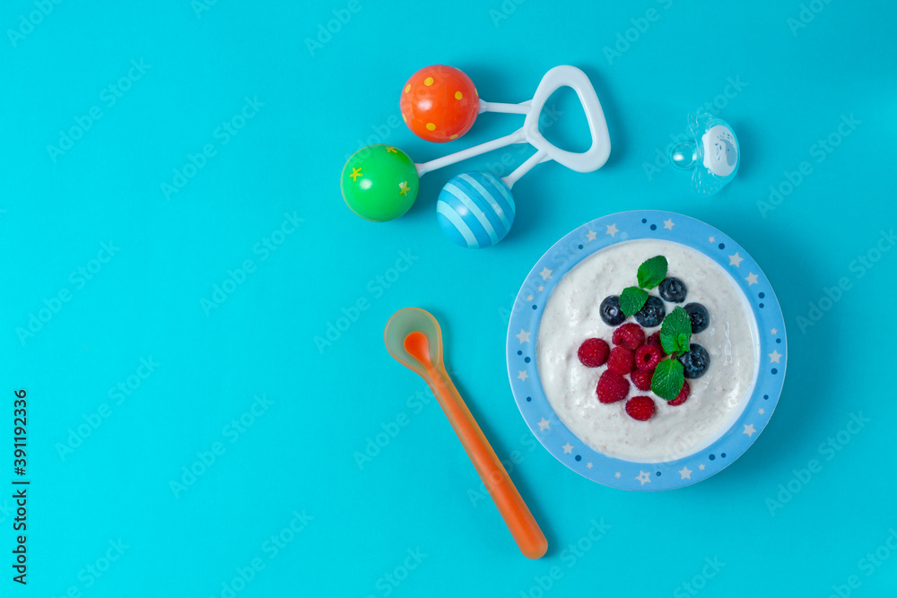 bowl with yogurt, for a child, with blueberries and raspberies, on a blue background, horizontal bowl with yogurt, for a child, with blueberries and raspberies, on a blue background, horizontal