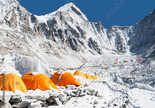 A group of orange tents at a climbers base camp in the Himalayas region.  photo