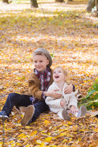 The elder brother and little sister are walking and laughing in the autumn park. Family and Children. Autumn mood 