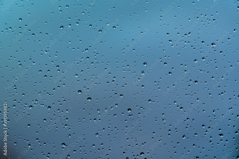 Water drops on window glass after rain. Macro of raindrops as abstract background with shallow depth of field. Concepts of rainy weather in autumn or winter season, cold temperatures and melancholy. Water drops on window glass after rain. Macro of raindrops as abstract background with shallow depth of field. Concepts of rainy weather in autumn or winter season, cold temperatures and melancholy.