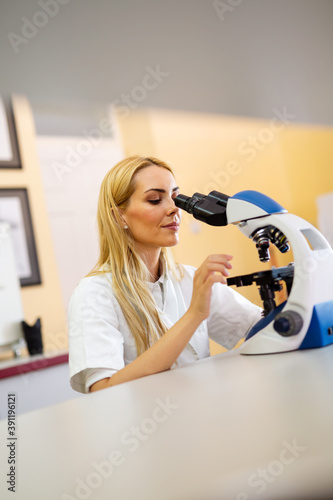 Young scientist woman working with microscope in a laboratory