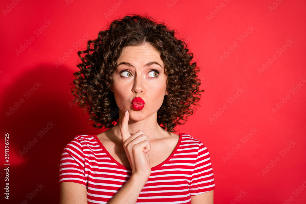 Photo of funny adorable wavy young woman dressed striped outfit finger chin looking empty space isolated red color background
